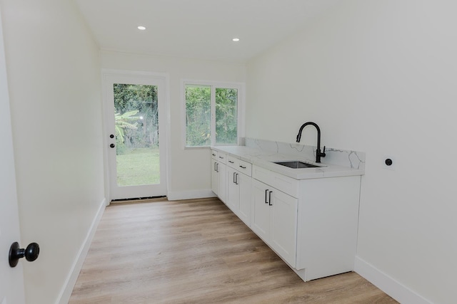 laundry area with cabinets, sink, and light wood-type flooring