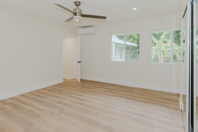 empty room with a wall mounted AC, ceiling fan, and light wood-type flooring