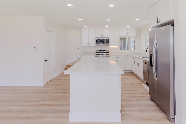 kitchen featuring white cabinets, appliances with stainless steel finishes, a center island, and light wood-type flooring