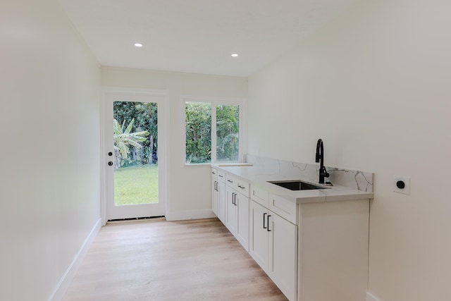 laundry room featuring hookup for an electric dryer, sink, light wood-type flooring, and cabinets