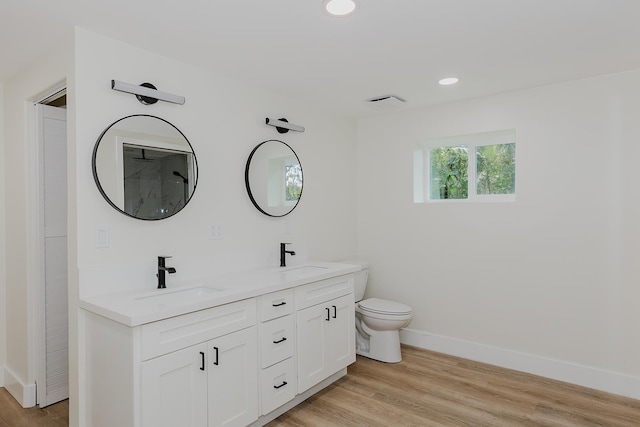 bathroom with hardwood / wood-style floors, toilet, and double sink vanity