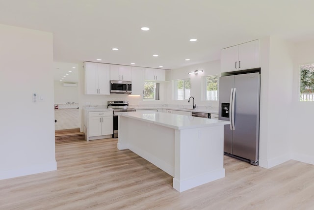 kitchen with appliances with stainless steel finishes, light hardwood / wood-style flooring, and white cabinetry