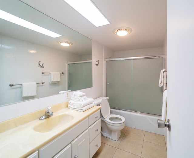 full bathroom with tile patterned floors, vanity, combined bath / shower with glass door, and toilet