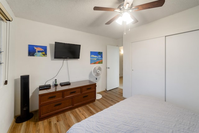 bedroom with a textured ceiling, light wood-type flooring, a closet, and ceiling fan