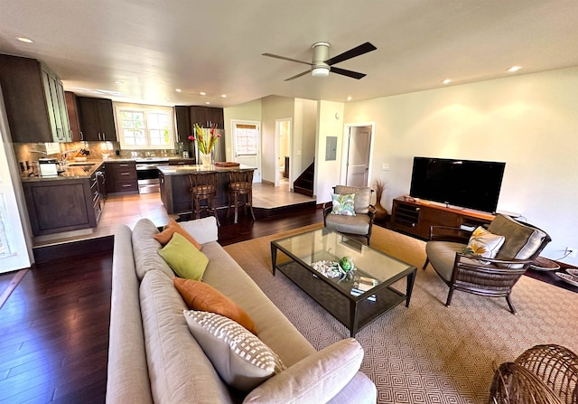 living room with ceiling fan, sink, and light wood-type flooring