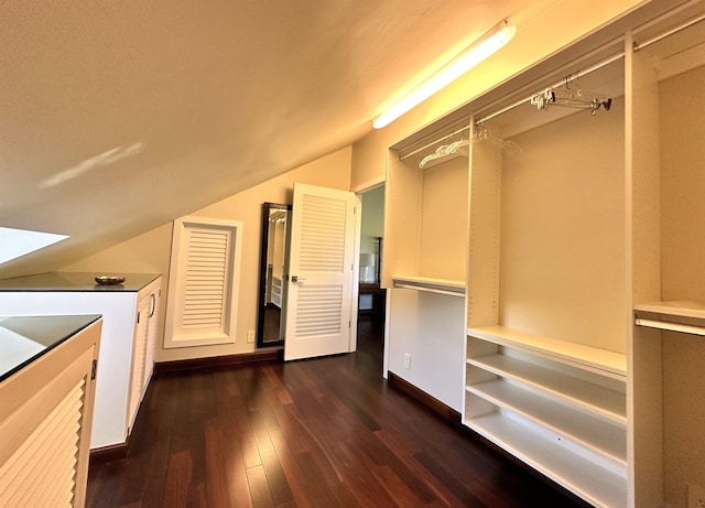 walk in closet with dark wood-type flooring and vaulted ceiling