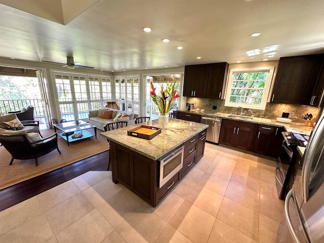 kitchen with plenty of natural light, a kitchen island, light stone counters, and appliances with stainless steel finishes