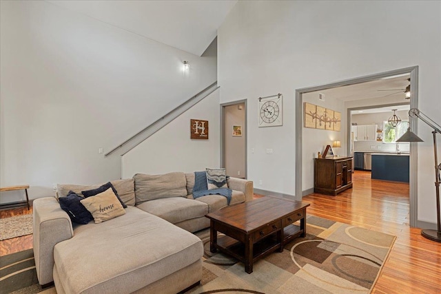 living room with ceiling fan, hardwood / wood-style floors, and a high ceiling