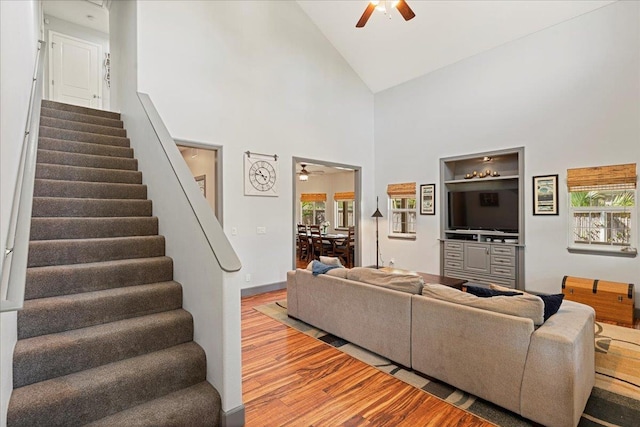 living room with ceiling fan, light hardwood / wood-style floors, and high vaulted ceiling