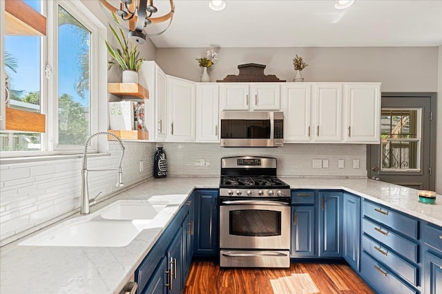 kitchen featuring appliances with stainless steel finishes, sink, blue cabinetry, hardwood / wood-style flooring, and white cabinetry