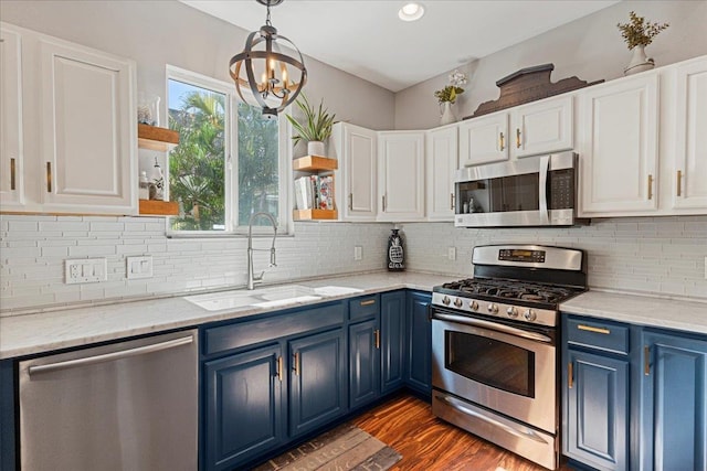 kitchen with appliances with stainless steel finishes, sink, blue cabinetry, white cabinetry, and hanging light fixtures