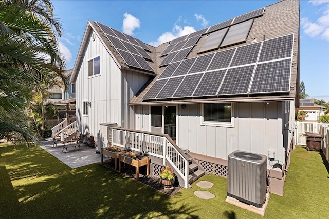 rear view of property with solar panels, a patio, central AC unit, and a yard