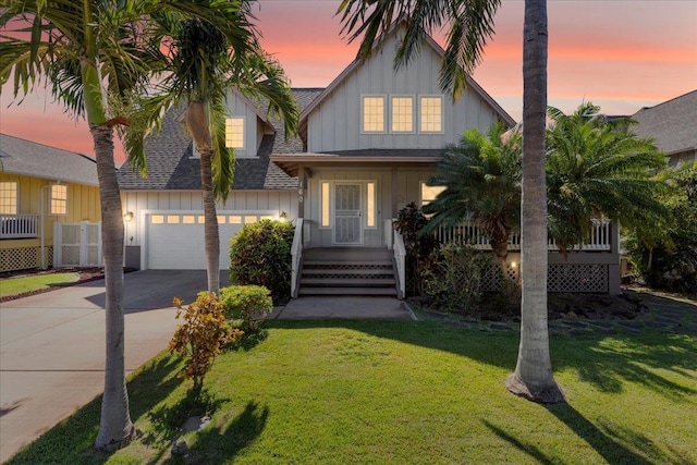 view of front of property featuring a lawn, a garage, and covered porch