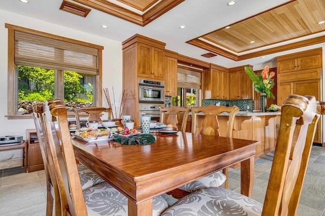 tiled dining space with plenty of natural light, a tray ceiling, and crown molding