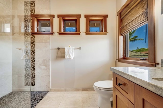 bathroom featuring tile patterned flooring, toilet, vanity, and tiled shower