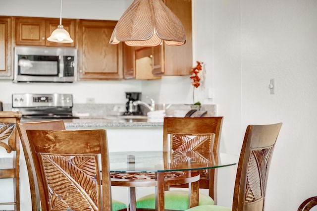 kitchen with decorative light fixtures, sink, and stainless steel appliances