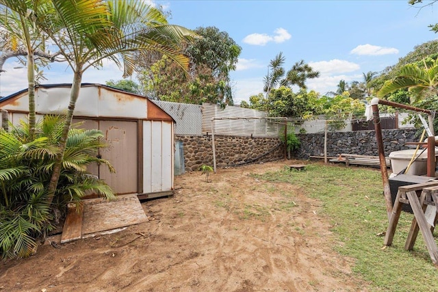 view of yard featuring an outdoor structure, a fenced backyard, and a storage shed