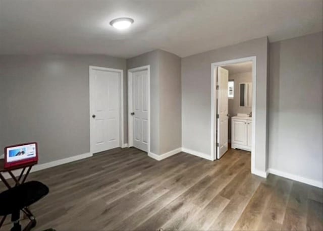 bedroom with dark wood finished floors, baseboards, and connected bathroom