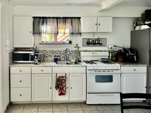 kitchen with white cabinets, white range with gas stovetop, tasteful backsplash, and a sink