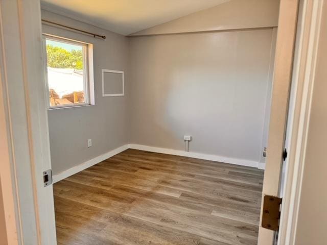 empty room with vaulted ceiling, wood finished floors, and baseboards