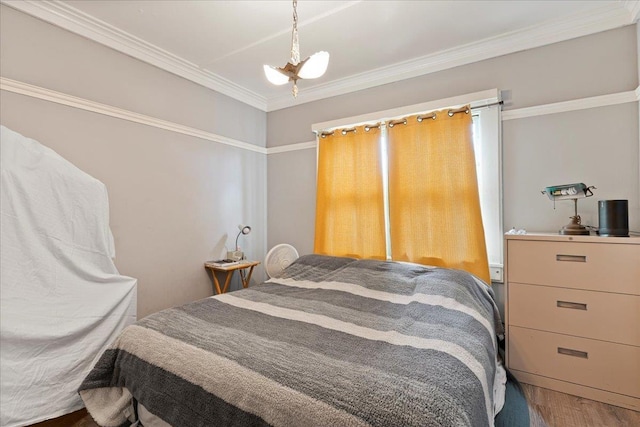 bedroom with an inviting chandelier, wood finished floors, and ornamental molding