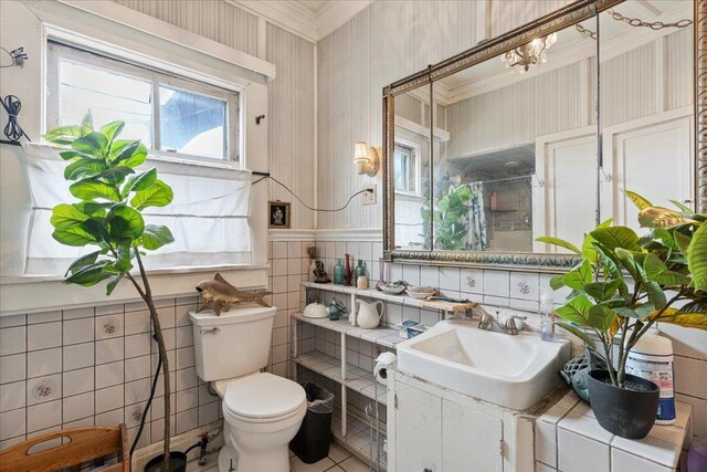 bathroom featuring wainscoting, vanity, toilet, and tile walls