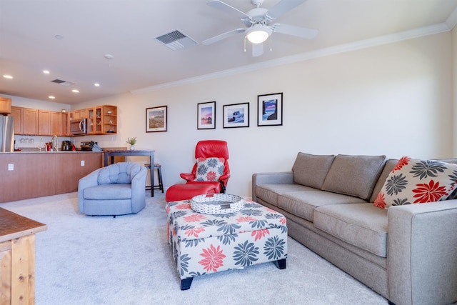 living area featuring ceiling fan, ornamental molding, visible vents, and light colored carpet