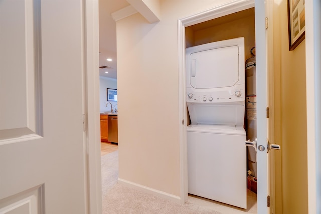 washroom with stacked washer and clothes dryer, recessed lighting, light colored carpet, laundry area, and baseboards