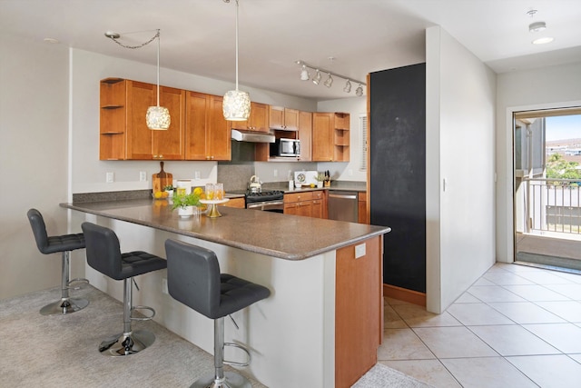 kitchen with a breakfast bar, kitchen peninsula, hanging light fixtures, stainless steel appliances, and light tile patterned floors