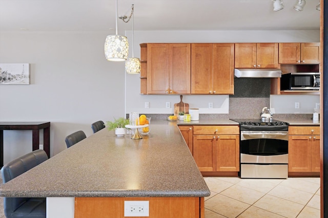 kitchen featuring light tile patterned flooring, a kitchen bar, stainless steel appliances, pendant lighting, and decorative backsplash