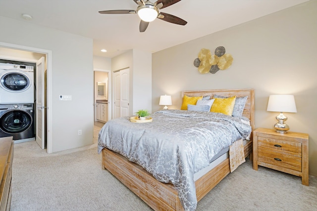 carpeted bedroom featuring connected bathroom, ceiling fan, a closet, and stacked washer and dryer