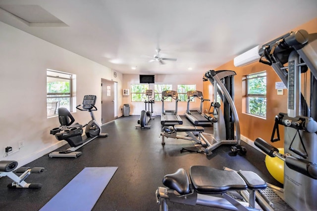 exercise room with ceiling fan, a wall mounted air conditioner, and plenty of natural light