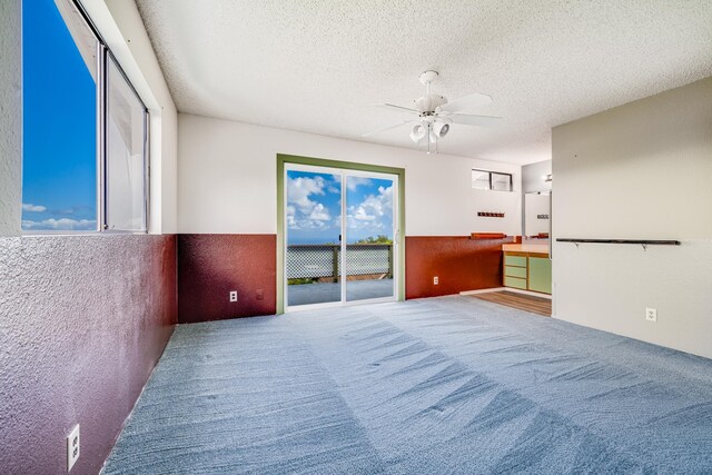 carpeted empty room featuring ceiling fan and a textured ceiling
