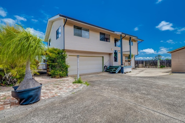 back of property featuring a garage, driveway, and fence