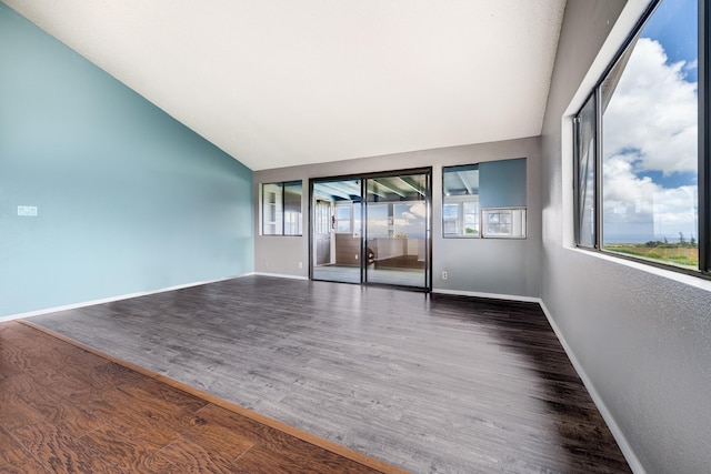 unfurnished room featuring baseboards, wood finished floors, and high vaulted ceiling