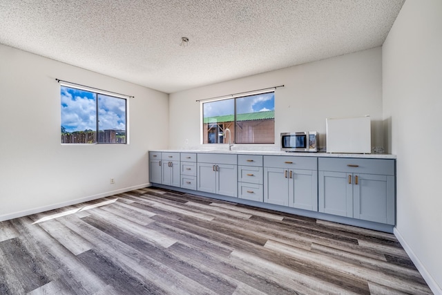 spare room featuring wood finished floors, a textured ceiling, baseboards, and a sink
