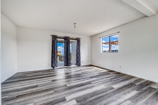 empty room with wood finished floors, a textured ceiling, and baseboards
