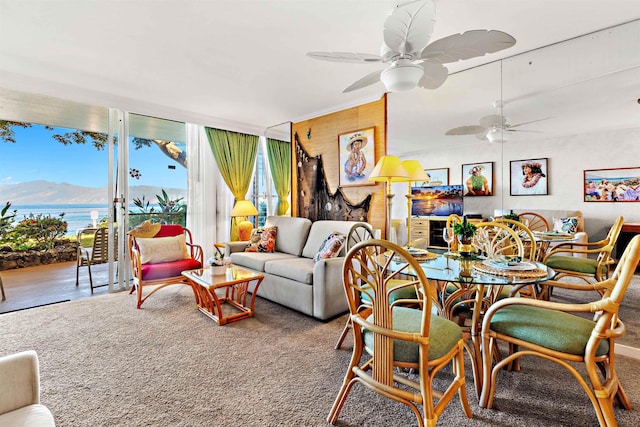 carpeted living room with a water view and ceiling fan