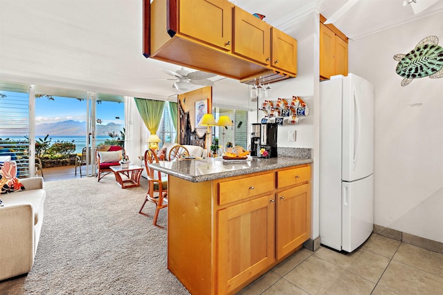 kitchen featuring ceiling fan, white refrigerator, kitchen peninsula, light tile patterned floors, and ornamental molding