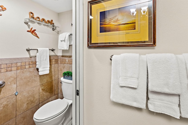 bathroom featuring tile walls and toilet