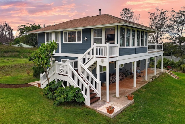 rear view of property with a patio area, a sunroom, and a yard