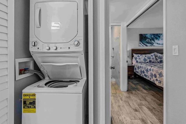 laundry area with hardwood / wood-style flooring and stacked washing maching and dryer