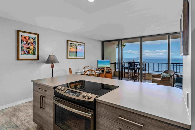 kitchen with stainless steel range with electric stovetop, dark brown cabinets, floor to ceiling windows, and light hardwood / wood-style flooring