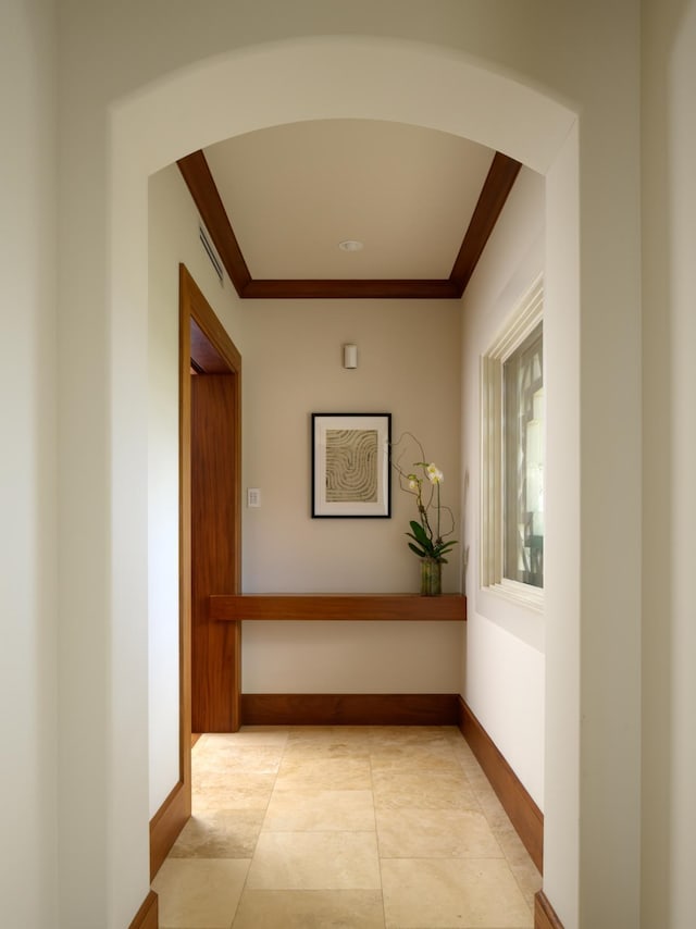 hall with visible vents, arched walkways, light tile patterned flooring, crown molding, and baseboards