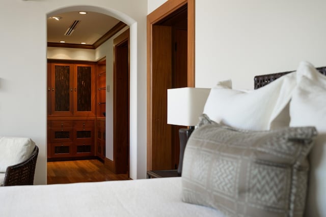 bedroom featuring visible vents, crown molding, recessed lighting, wood finished floors, and arched walkways