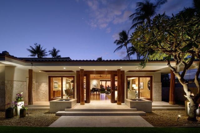 back of property at dusk featuring stucco siding