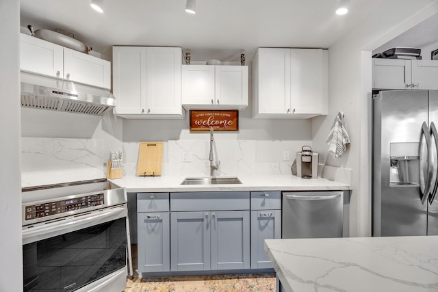 kitchen featuring sink, tasteful backsplash, white cabinetry, stainless steel appliances, and light stone countertops