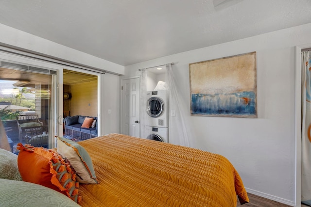 bedroom featuring hardwood / wood-style floors, access to outside, and stacked washer and clothes dryer