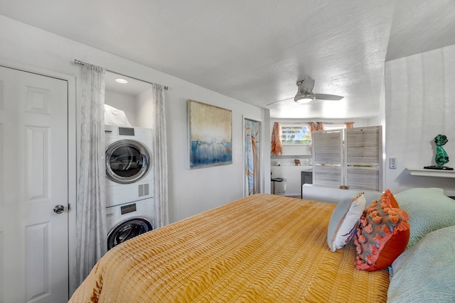 bedroom featuring ceiling fan and stacked washer / dryer