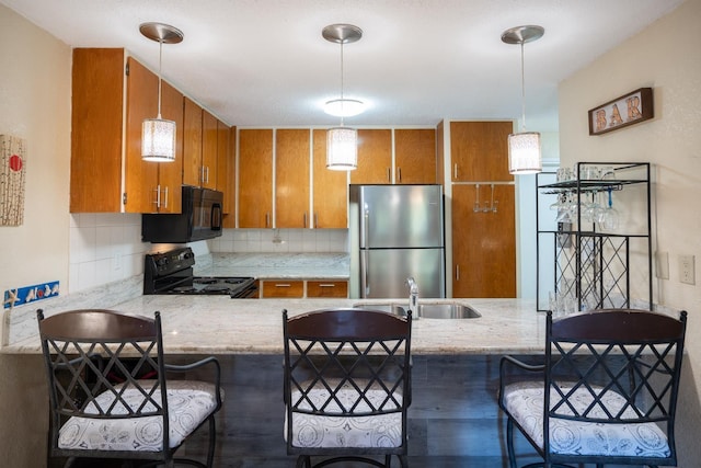 kitchen with tasteful backsplash, sink, pendant lighting, and black appliances